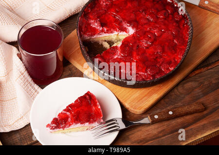 Ein Stück Käsekuchen mit roter Marmelade und Beeren auf eine weiße Platte mit einer Gabel, Ansicht von oben Stockfoto