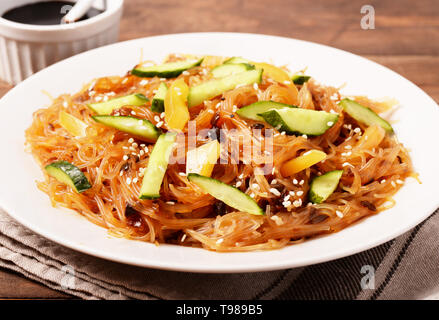 Asiatisches Restaurant gesundes Essen. Funchoza mit Fleisch und Gemüse, Sojasauce, Paprika und Gurke auf Platte closeup Stockfoto