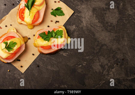 Sandwich mit Schinken, Käse und Tomaten close-up auf schwarzem Hintergrund Stockfoto