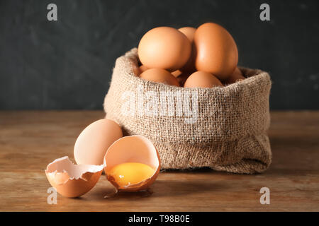 Sack mit rohem Huhn Eier auf hölzernen Tisch Stockfoto