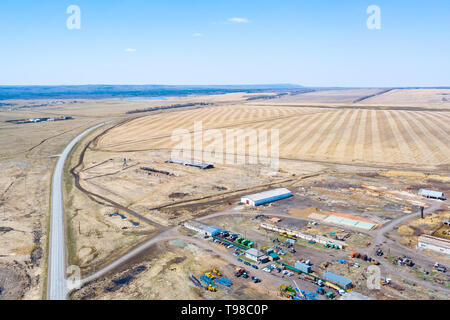 Luftaufnahme auf landwirtschaftliche Maschinen in der Nähe des Hangars im Dorf für Pflanzung und Ernte. Agrar- und Landwirtschaft mit der Straße, die in die Stockfoto