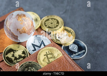 Blick auf unterschiedliche Art von Metall bitcoins aus braunem Leder Brieftasche und Glas Globus. Konzept Bild für cryptocurrency Stockfoto