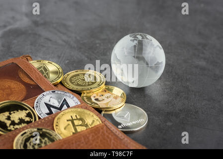 Blick auf unterschiedliche Art von Metall bitcoins aus braunem Leder Brieftasche und Glas Globus. Konzept Bild für cryptocurrency Stockfoto