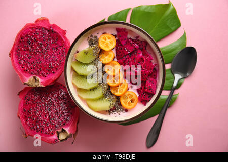 Joghurt mit verschiedenen Früchten in Schüssel auf farbigen Hintergrund Stockfoto