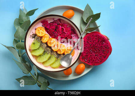 Joghurt mit verschiedenen Früchten in Schüssel auf farbigen Hintergrund Stockfoto