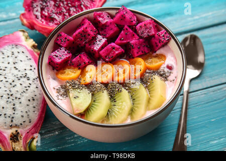 Joghurt mit verschiedenen Früchten in der Schüssel auf hölzernen Hintergrund Stockfoto