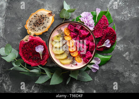 Joghurt mit verschiedenen Früchten in der Schüssel auf grauem Hintergrund Stockfoto