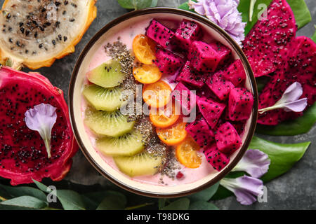 Joghurt mit verschiedenen Früchten in der Schüssel auf grauem Hintergrund Stockfoto