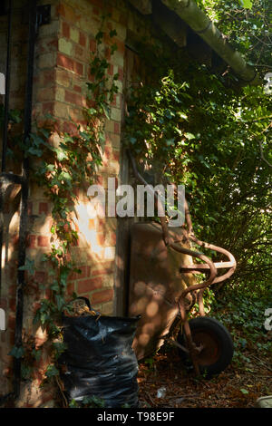 Moody abstract von gardners Schubkarre in dappled Licht auf dem Gelände des St. Laurance, Henley-in-arden, Alcester, Warwickshire Stockfoto