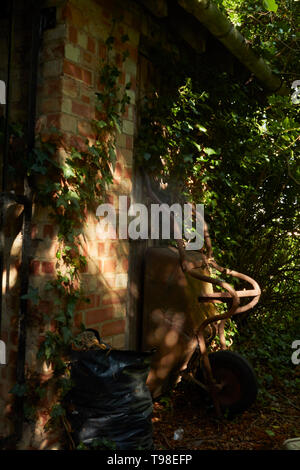 Moody abstract von gardners Schubkarre in dappled Licht auf dem Gelände des St. Laurance, Henley-in-arden, Alcester, Warwickshire Stockfoto