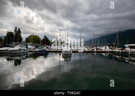 Viele Boote Yachten und Segelboote günstig auf einem Dock in einem Hafen auf einer dunklen bewölkten Himmel. Stockfoto