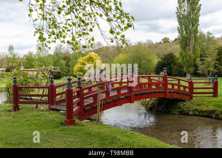 Rote hölzerne Fußgängerbrücke in den Gärten von Heale House, Woodford, Wiltshire, England, Großbritannien Stockfoto