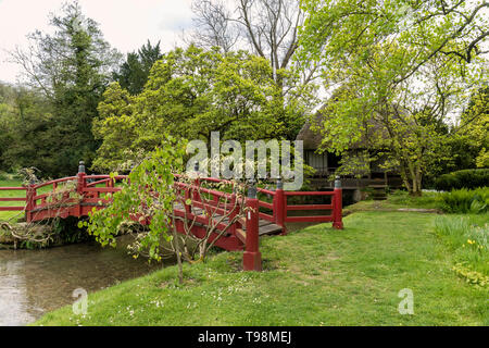 Rote hölzerne Fußgängerbrücke in den Gärten von Heale House, Woodford, Wiltshire, England, Großbritannien Stockfoto