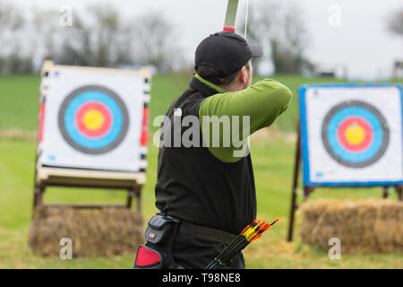 Archer üben Feldbogenschießen vorbereitet, seinen Pfeil auf ein Ziel zu verlieren. Stockfoto