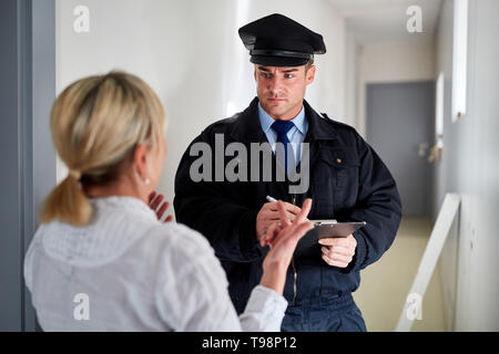 Polizist spricht mit Frau Zeugnis Interview an der Haustür nach einem Einbruchdiebstahl Stockfoto