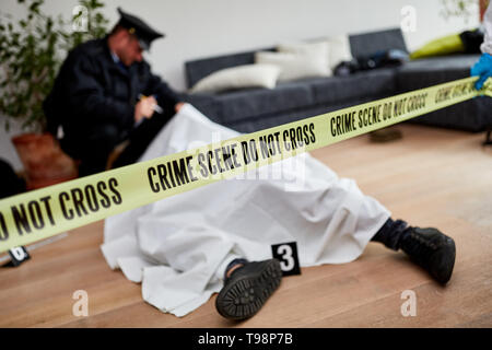 Polizist neben dem toten Körper untersucht Mord am Tatort Stockfoto
