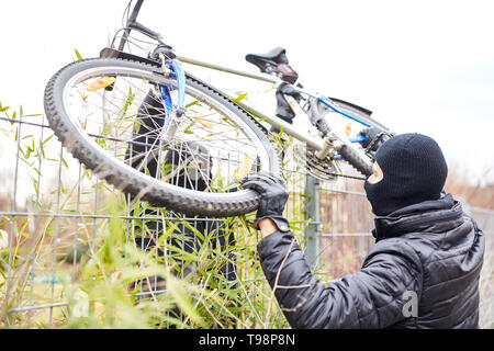 Zwei Diebe in der fahrraddiebstahl in der Stadt mit dem Fahrrad über einen Zaun Stockfoto