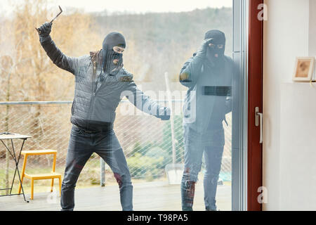 Einbrecher schlagen Festplatte einer Tür auf der Terrasse des Hauses bei Einbruch Stockfoto