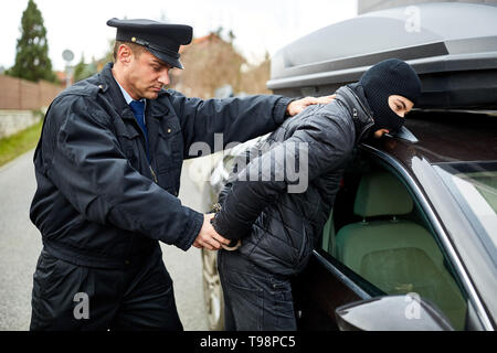 Polizeibeamte Verhaftungen Autodieb in der Akte und ihm Handschellen auf Anhalten Stockfoto