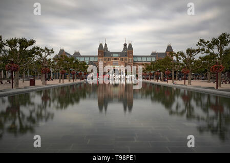 Atemberaubende Landschaft Bild des Rijksmuseum und das Spiegelbild im Wasser mit der iamsterdam signage vor dem Museum Stockfoto