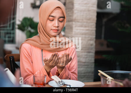 Hijab Frauen zusammen beten vor dem Essen, eine schnelle brechen Mahlzeit auf einem Tisch im Garten serviert. Stockfoto