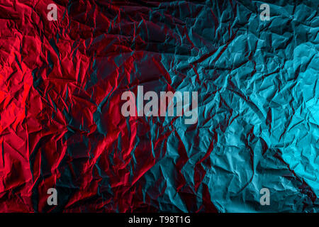 Textur von Zerknitterten schwarzen Papier. In der Nähe von Schwarzen Hintergrund der Zerknüllten Karton unter Farbe rot und blau Studio Light Stockfoto