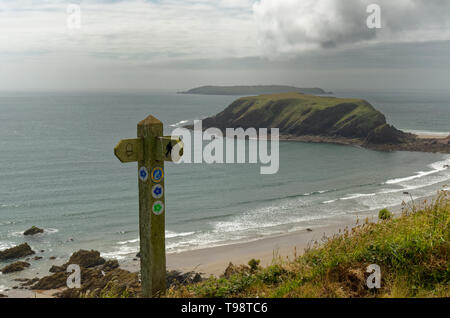 Blick vorbei an einem Pembrokeshire Coast Path Marker Post nach Gateholm Island und Skokholm, in der Nähe von Martin's Haven auf der Marloes-Halbinsel in Wales Stockfoto