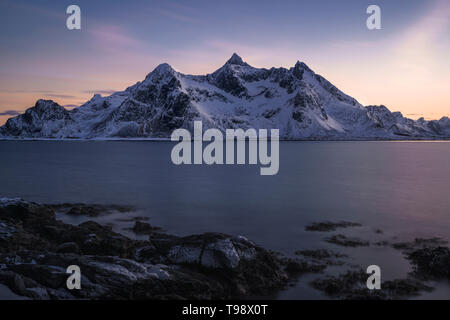 Weiche Töne der blauen Stunde mit Bergen an der Küste von Vareid, Lofoten, Norwegen Stockfoto