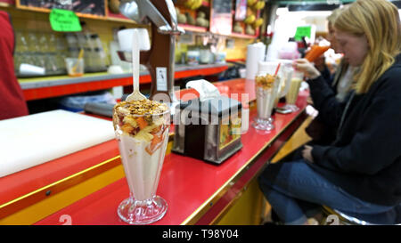 Jugos Canadå, Mexiko Stadt. Saftbar. Tropische Joghurt Schale mit Honig, Müsli, Ananas, Papaya und andere Früchte. Blonde Mädchen rote an der Theke sitzen. Stockfoto