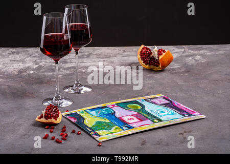 Zwei Gläser Rotwein mit einem Granatapfel und Bild auf schwarzem Hintergrund Stockfoto