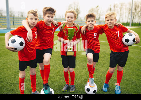 Gerne Jungen in Fußball-Team. Kinder in der Schule Fußball Sport Team Holding goldene Trophäe und Fußbälle. Gruppe von Kindern in den Fußball-Team in F Stockfoto