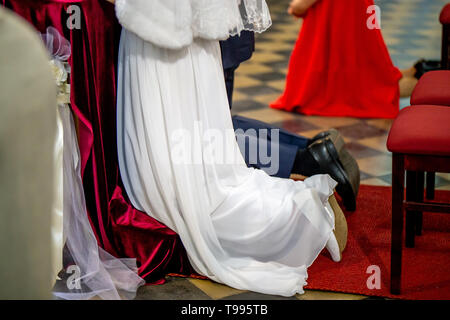 Braut und Bräutigam Vorbereitung der Gemeinschaft auf die Knie bei der Trauung in der Kirche. Braut und Bräutigam während der Trauung in der Kirche. Stockfoto