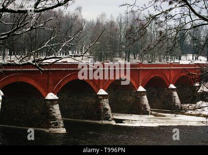 Red brick Brücke über den teilweise zugefrorenen Fluss Venta in Kuldīga. Stockfoto