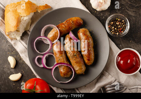 Gegrillte Würstchen mit Sauce Ketchup auf einem Holztisch. Ansicht von oben. Stockfoto