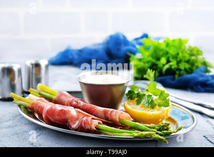 grüner Spargel mit Speck auf einem Tisch Stockfoto