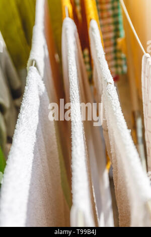 Weiße und farbige Bettwäsche und Handtücher auf der Wäscheleine getrocknet werden. Stockfoto