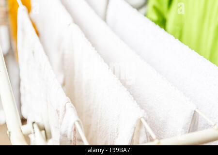 Weiße und farbige Bettwäsche und Handtücher auf der Wäscheleine getrocknet werden. Stockfoto