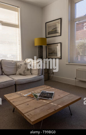 Ein modernes, helles Wohnzimmer in English home mit hölzernen Couchtisch und Interior Design Zeitschriften in den Vordergrund und