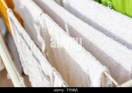 Weiße und farbige Bettwäsche und Handtücher auf der Wäscheleine getrocknet werden. Stockfoto