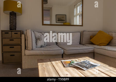 Ein modernes, helles Wohnzimmer in English home mit hölzernen Couchtisch und Interior Design Zeitschriften in den Vordergrund und Stockfoto