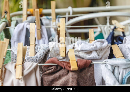 Weiße und farbige Bettwäsche auf die Wäscheleine mit Wäscheklammern aus Holz zu trocknen. Stockfoto