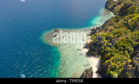 Tropische Insel mit weißem Strand und Korallenriff. Touristische boote in der Nähe der Insel. Nationalpark El Nido Palawan Philippinen. Stockfoto