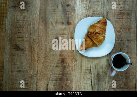 Tasse Kaffee und frisch gebackene Croissants auf Holz- Hintergrund. Ansicht von oben. Beispiel für ein Frühstück Stockfoto