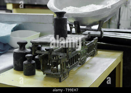 Alte Waage mit Gewichten und einer Schüssel mit Mehl. Retro Ausrüstung in die Bäckerei. Vintage-Technologie. Stockfoto