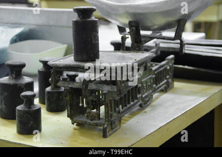 Alte Waage mit Gewichten und einer Schüssel mit Mehl. Retro Ausrüstung in die Bäckerei. Vintage-Technologie. Stockfoto