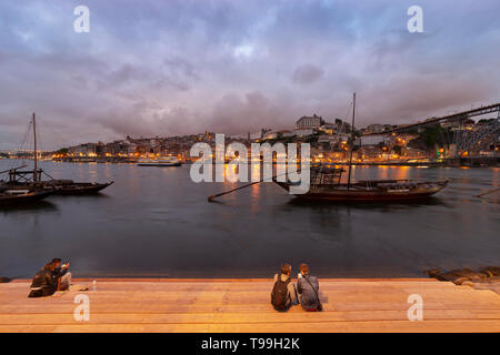 Blick über den Rio Douro in der Dämmerung nach Porto mit traditionellen Hafen Boote im Vordergrund. Stockfoto