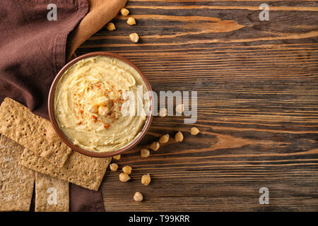 Schüssel mit leckerem Hummus auf hölzernen Tisch Stockfoto