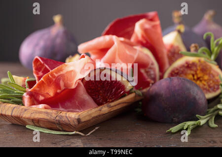 Reife saftige Feigen mit Prosciutto und Rosmarin. Stockfoto