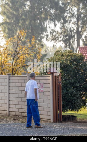 Johannesburg, Südafrika - ein nicht identifizierter älteren weißen Hausbesitzer vor dem Tor zu seinem Eigentum Bild im Hochformat Stockfoto