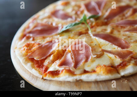 Pizza mit Schinken und Basilikum Stockfoto